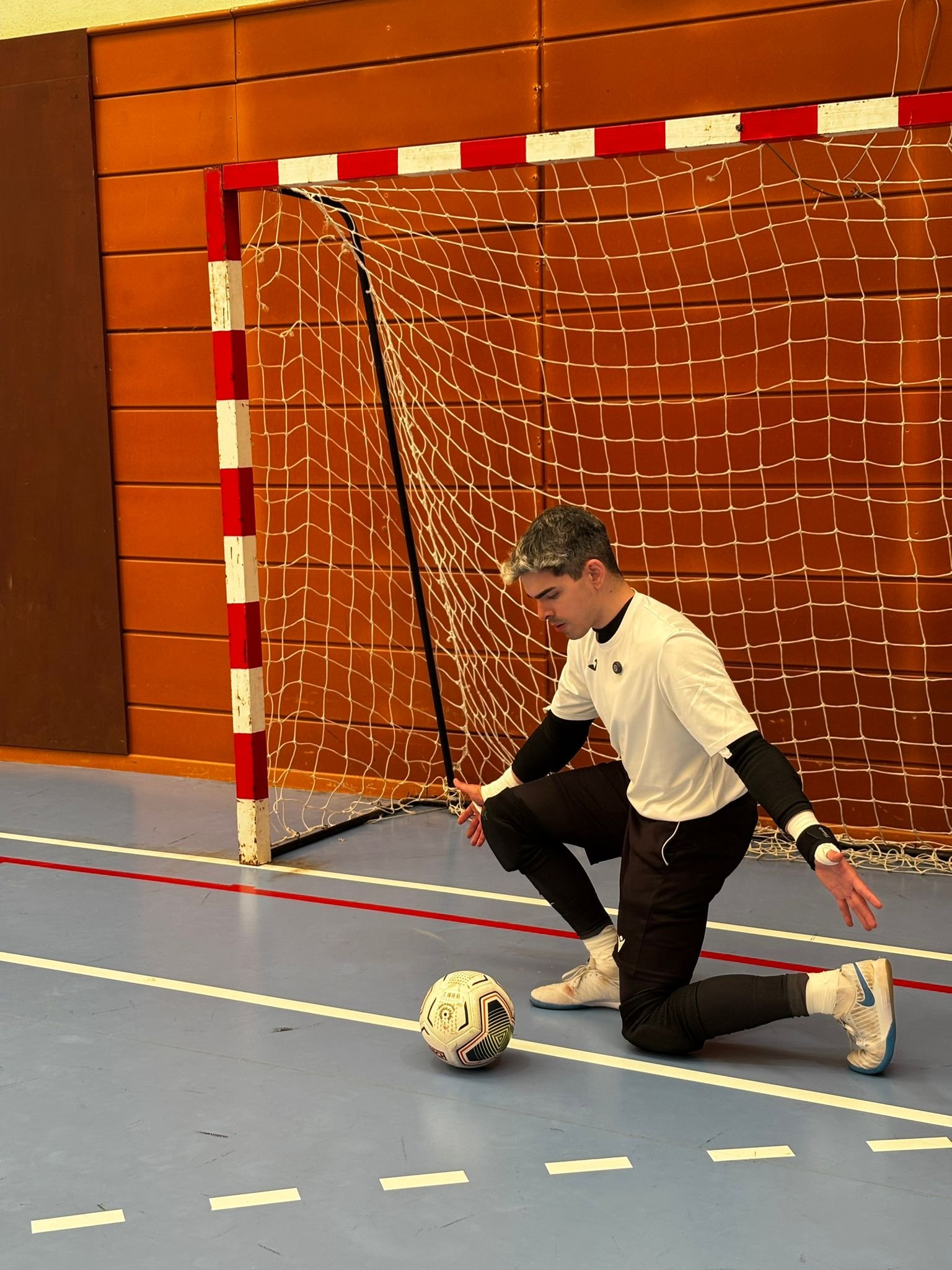 Portero de futsal ejecutando la tecnica de la cruz con seguridad